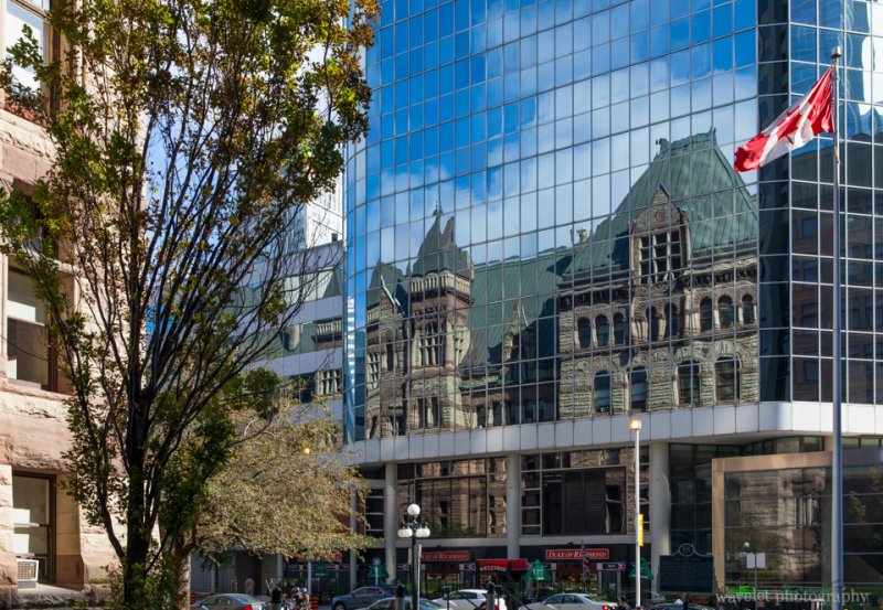 The Old City Hall reflected on the glass exterior of Eaton Centre, Toronto