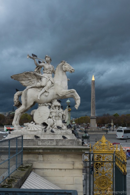 The statue of Renommée riding Pegasus at the west entrance of the Tuileries Garden and the Luxor Obelisk at the Place de la Concorde, Paris